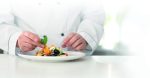 Male chef making tasty salad in kitchen, closeup